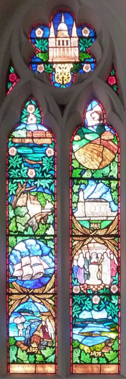 This is the 'Pioneer Window'. The left-hand side commemorates the early pioneers, showing Charles Fremantle's ship HMS Challenger, and the colony in 1829 in the bottom panel. The right-hand side represents the commemorates of the founding of St John's, showing the 1843 church that preceded this one, and a font very like the one in the current church. The last frame shows a view of Fremantle from the west, including the river, Willis Point, and the 1866 bridge – and the date 1875. The dedication at the bottom reads: 'To the Glory of God and in memory of the many pioneering families who settled in Fremantle. Presented by the donors, Thelma and David Johnson 1973.'