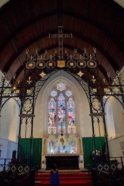 The rood screen through which may be seen the choir, the east window and altar with reredos. The IHS below the cross (rood) is a Christogram: the Greek letters iota, eta, and sigma are the first three in the title Christos (ΙΗΣΟΥΣ), meaning 'annointed'.