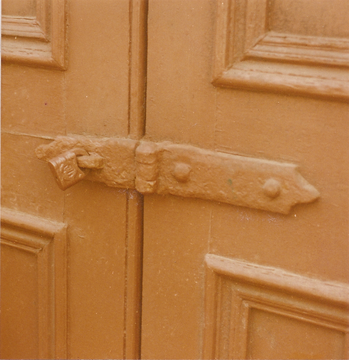 Corrosion has fused old hasp and padlock on aged doors.
